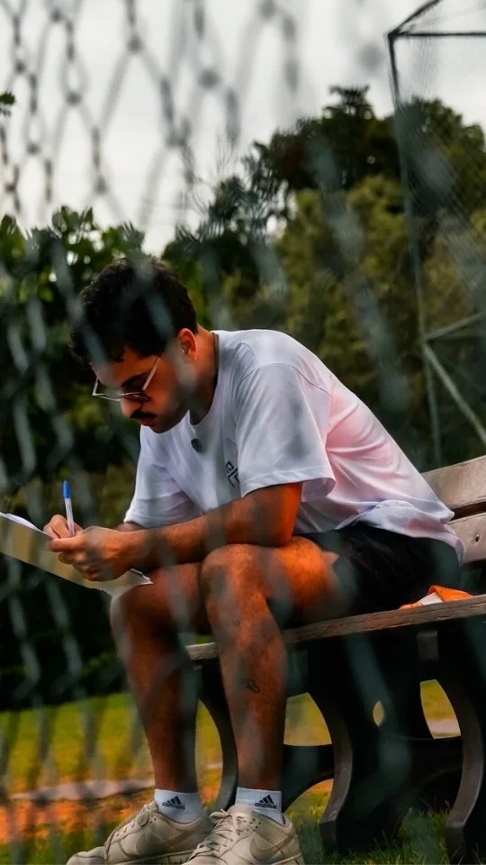 Pessoa com camiseta do NaTrave! faz anotações em papel na lateral do campo