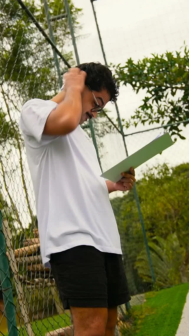 Pessoa com camiseta do NaTrave! consulta uma prancheta junto à grade do campo